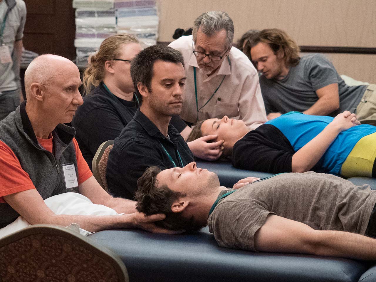 People lay on treatment tables while others hold their heads with both hands