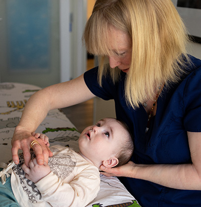 A woman holds the back of a baby’s head and chest 